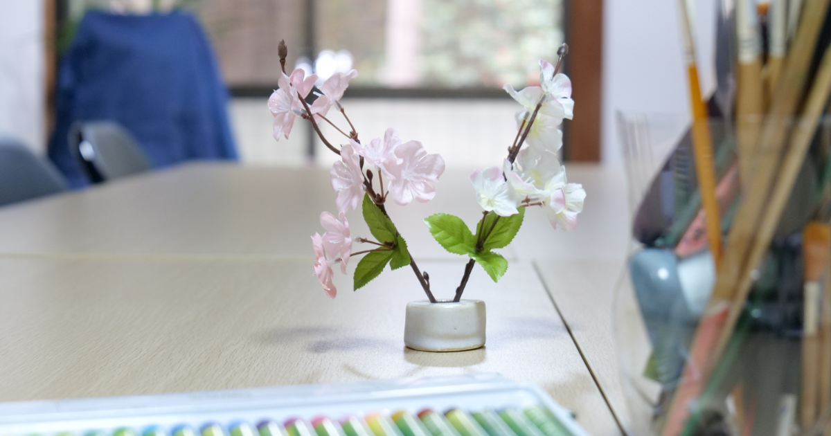 絵画教室の机の上に置かれた桜の枝。春の体験キャンペーンの雰囲気を演出。